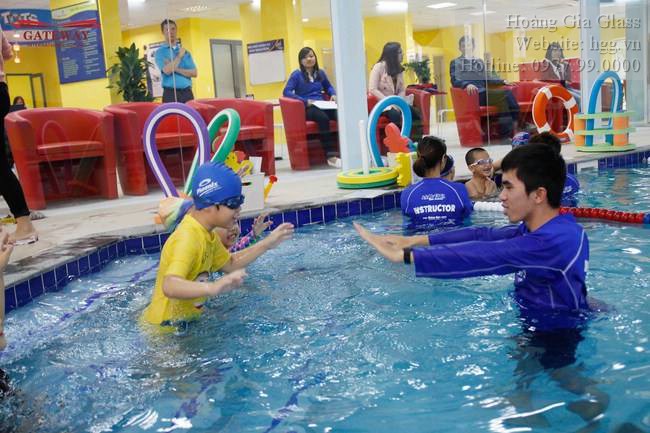 Giáo viên hướng dẫn các bé tại bể bơi ngăn bằng vách kính